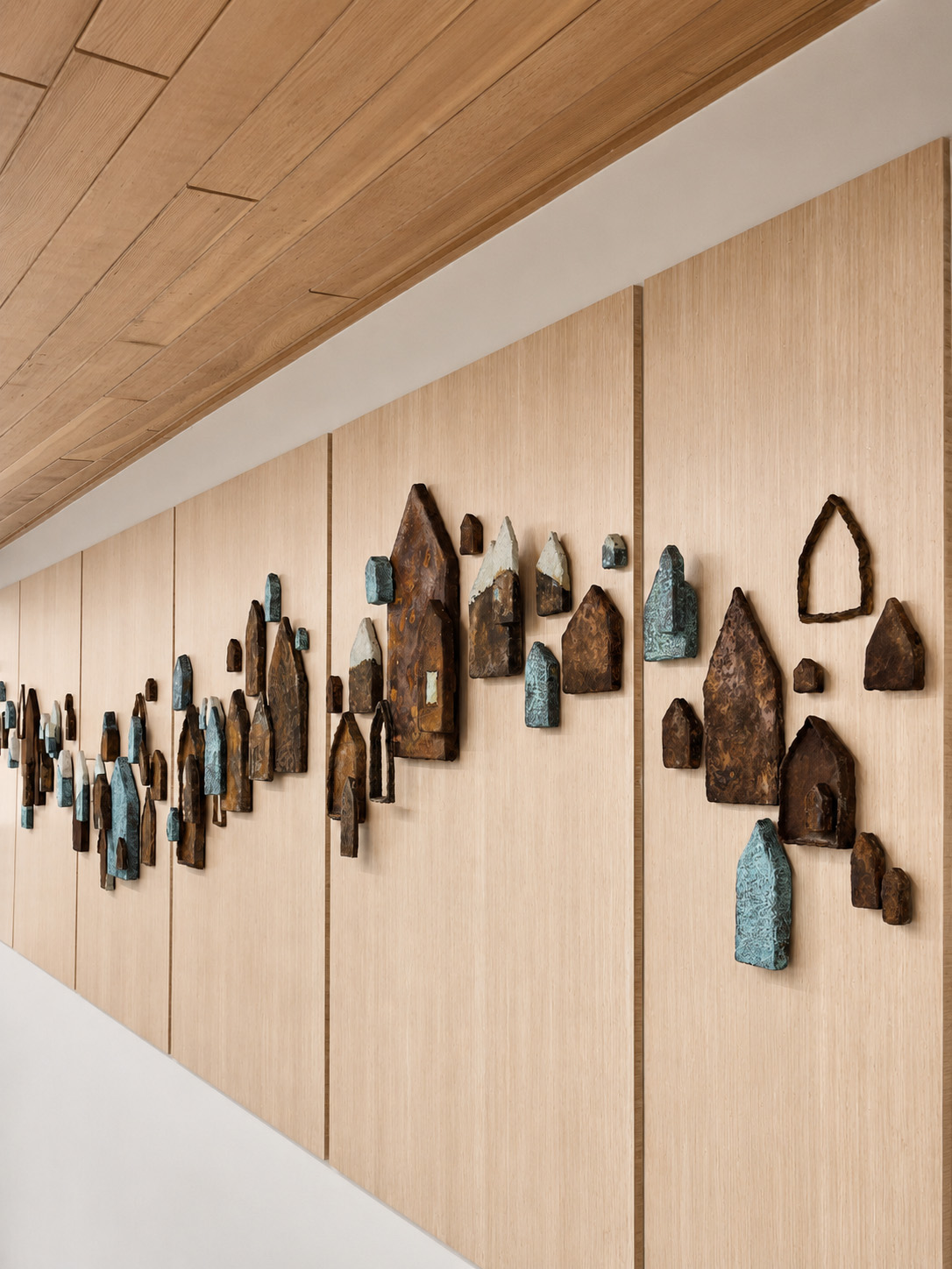 Saints and Poets, Maybe — three-quarter angle along the installation showing the dimensional forms coming off the wall