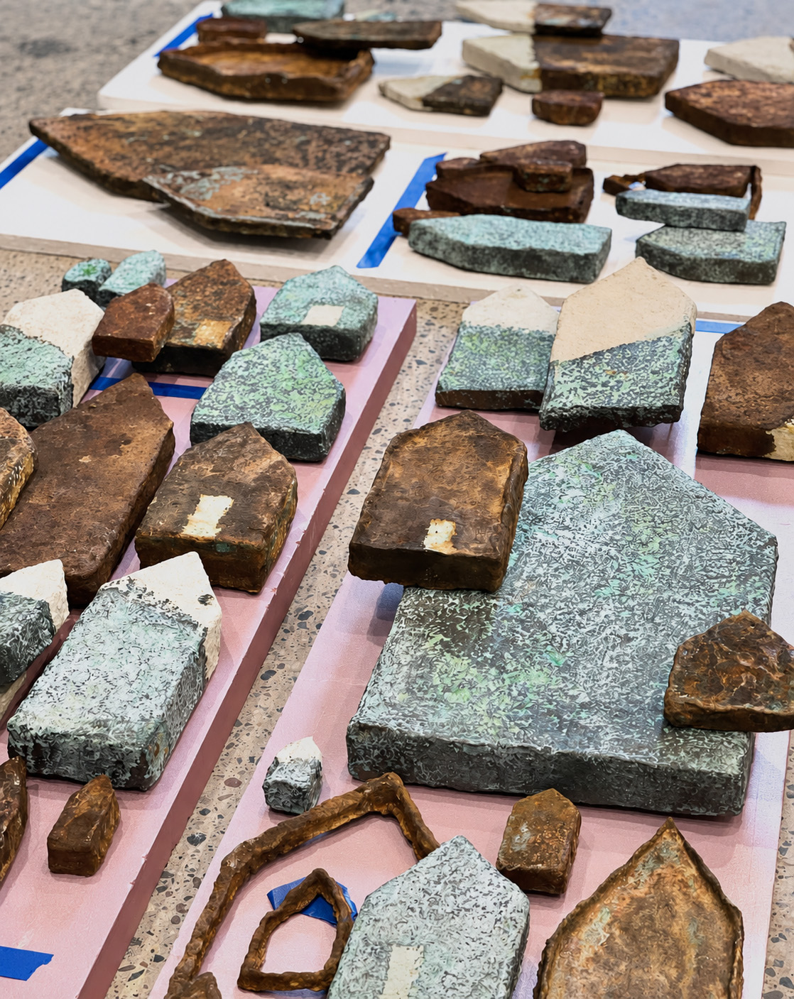 Saints and Poets, Maybe — close studio view of individual ceramic house forms with patinated bronze and iron oxide finishes